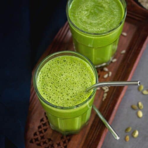 square image of green smoothie served in two glasses