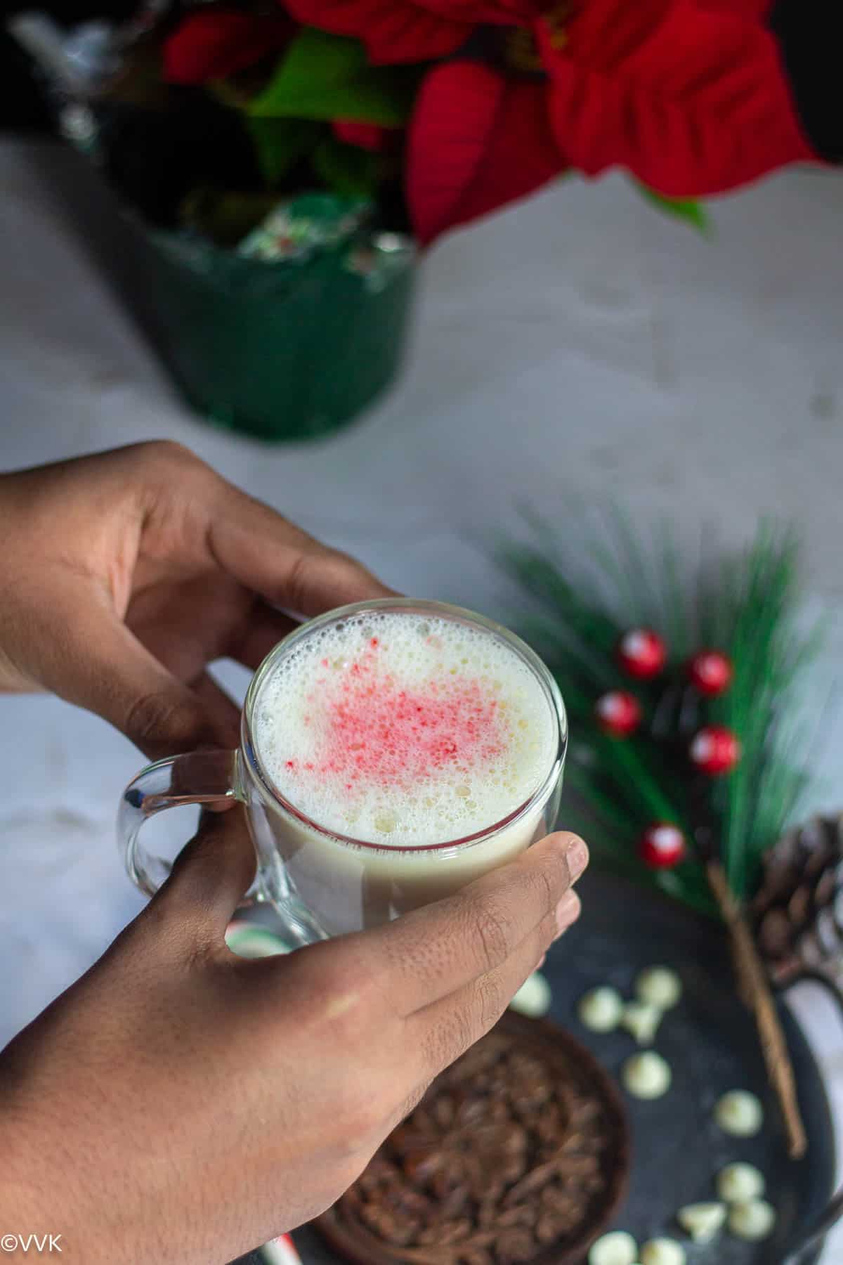 handheld shot of white hot chocolate topped with peppermint