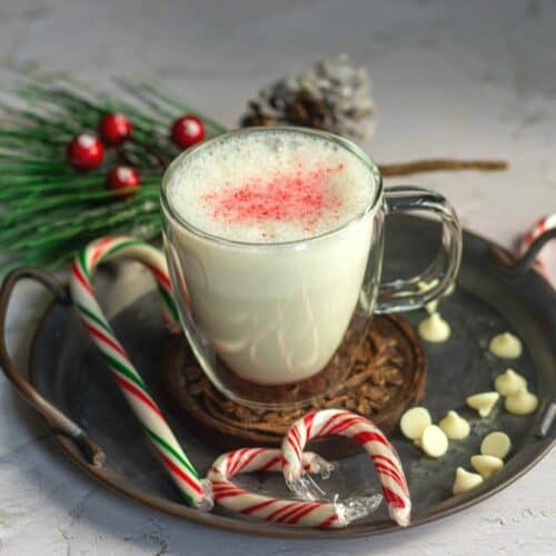 peppermint white hot chocolate served in a mug with some candy canes and white chocolate on the side