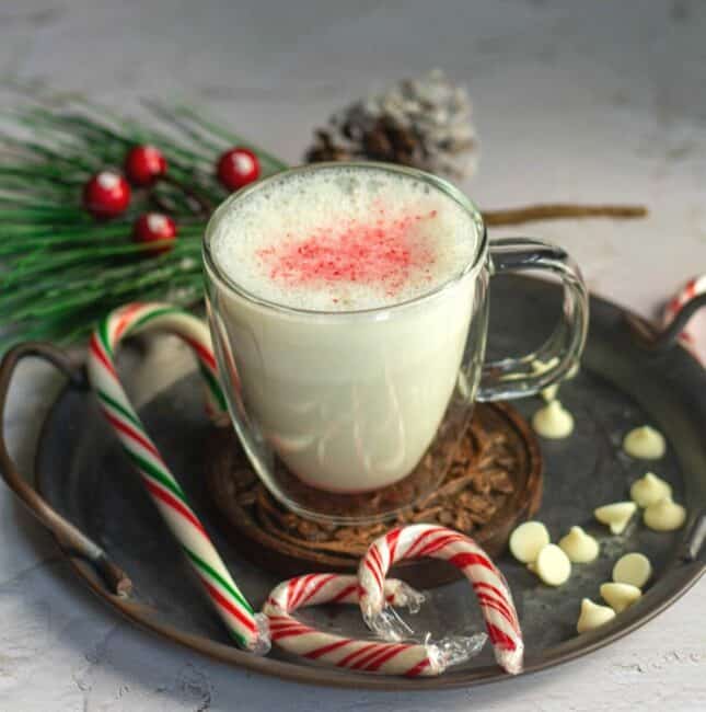 peppermint white hot chocolate served in a mug with some candy canes and white chocolate on the side