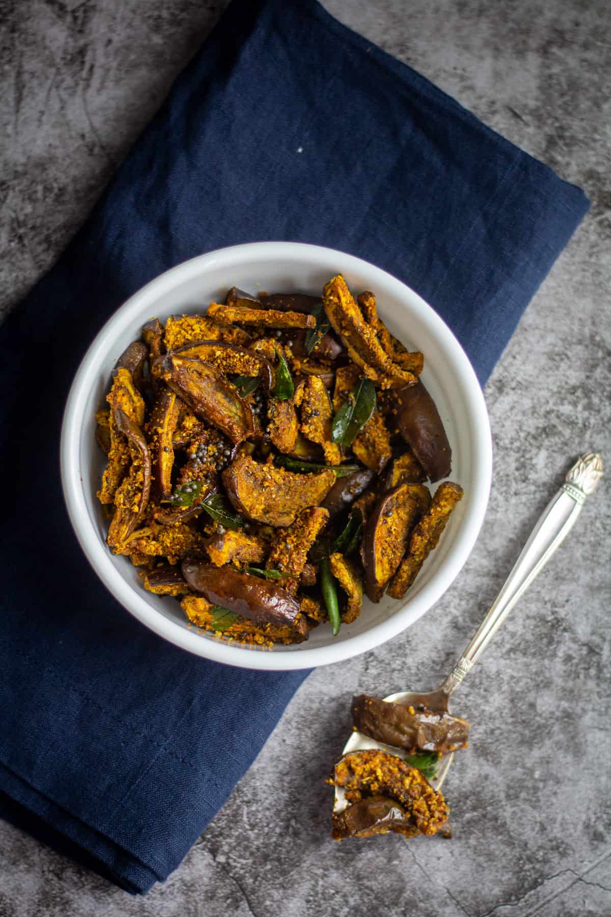 easy air fryer brinjal served in white bowl with spoon ful of curry on the side