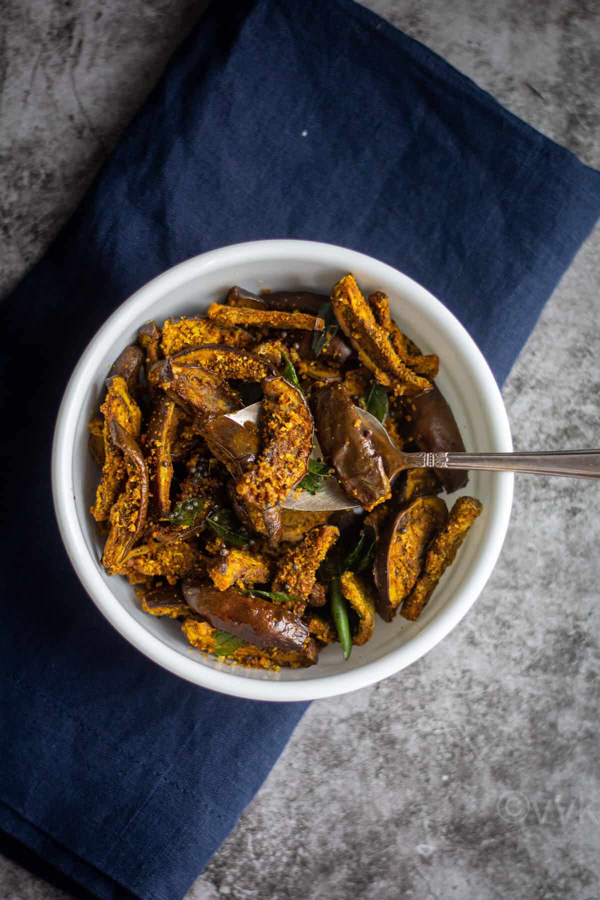 air fryer brinjal roast served in white bowl with spoon inside