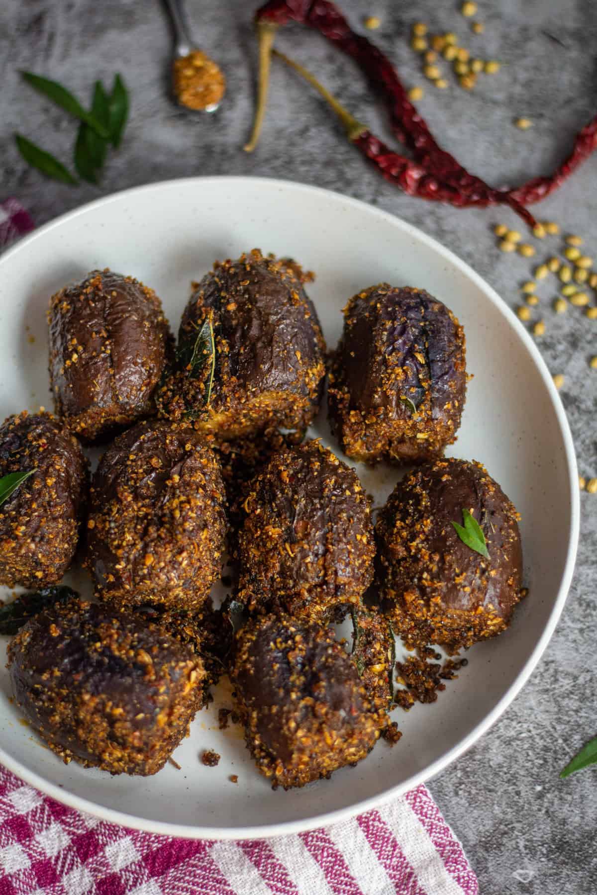 south indian stuffed brinjal served in white bowl with spices sprinkled on the side