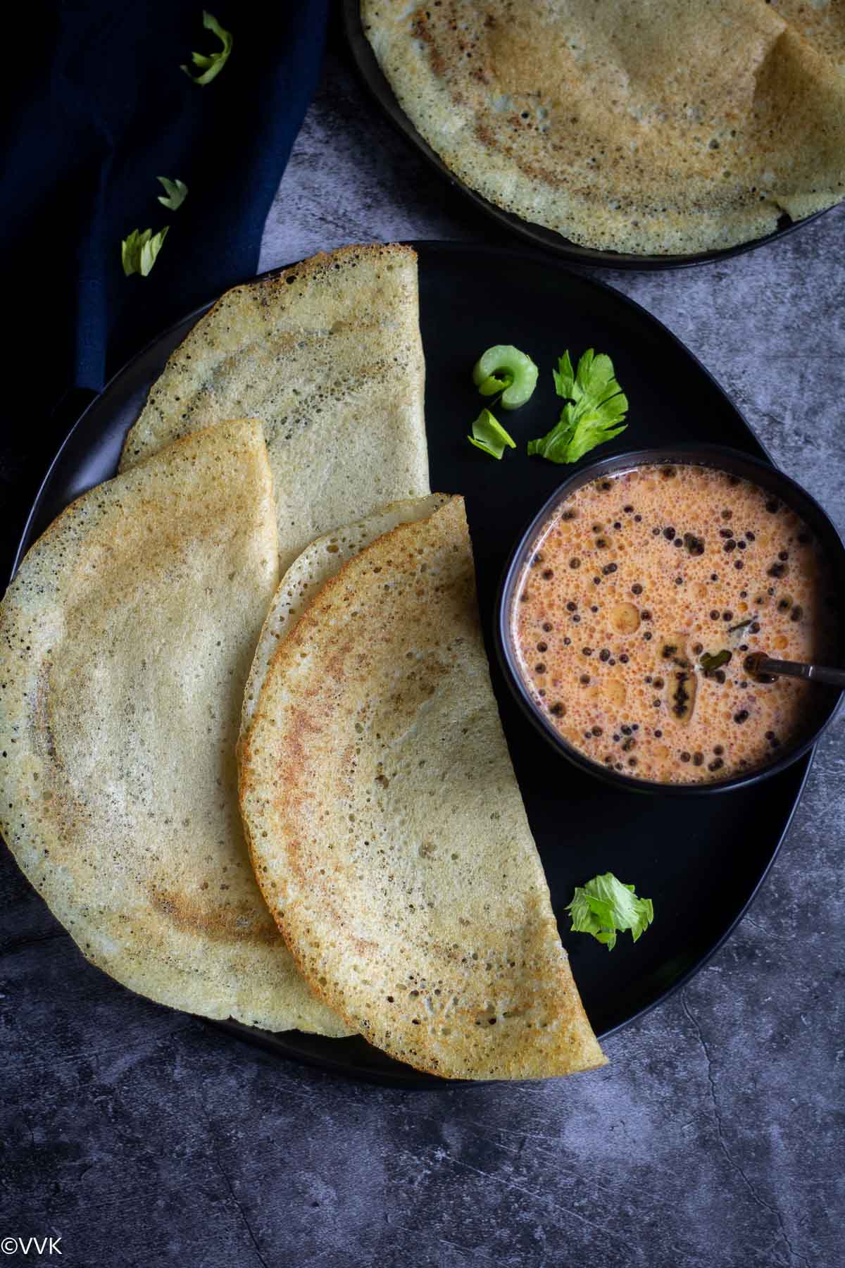 healthy celery dosa served in black plate with chutney on the side in a bowl
