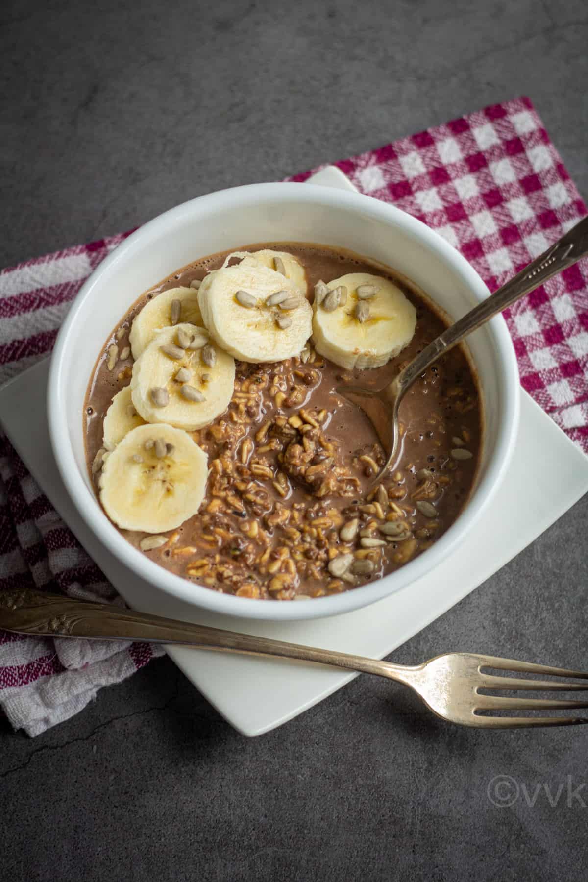 chocolate overnight oats served in white bowl topped with banana and sunflower seeds