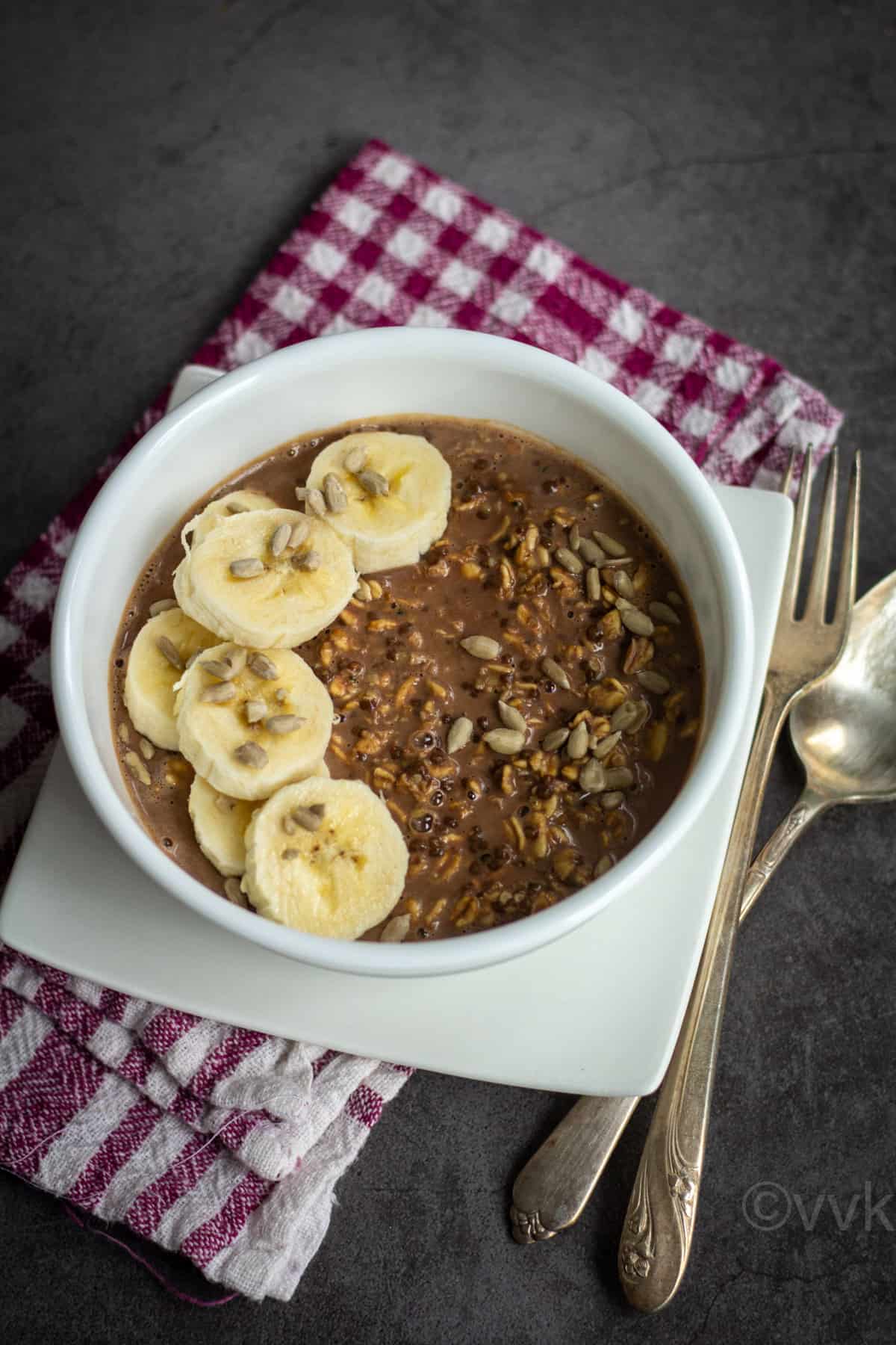 easy and simple overnight oats served in white bowl topped with banana and sunflower seeds