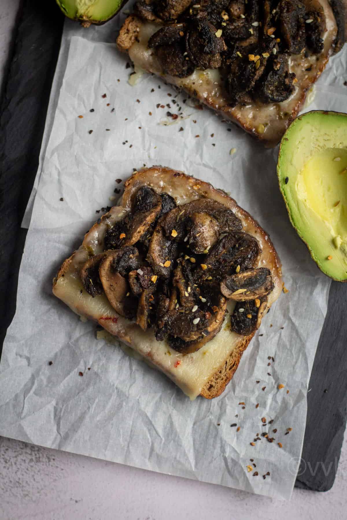 quick and easy mushroom toast served on crumbled parchment paper with avocado on the side