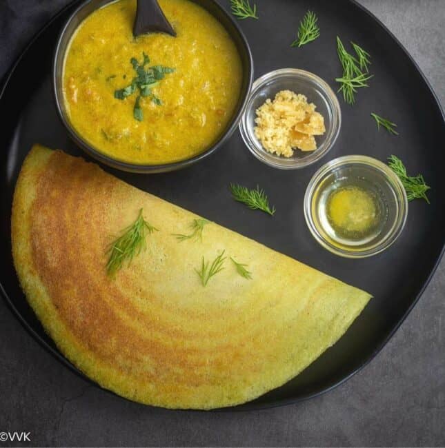 dill dosa served with kurma, jaggery and ghee placed on a black plate