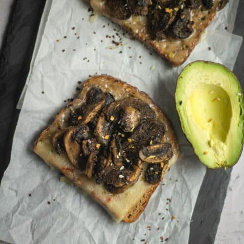 mushroom toast served with avocado placed on a parchment paper