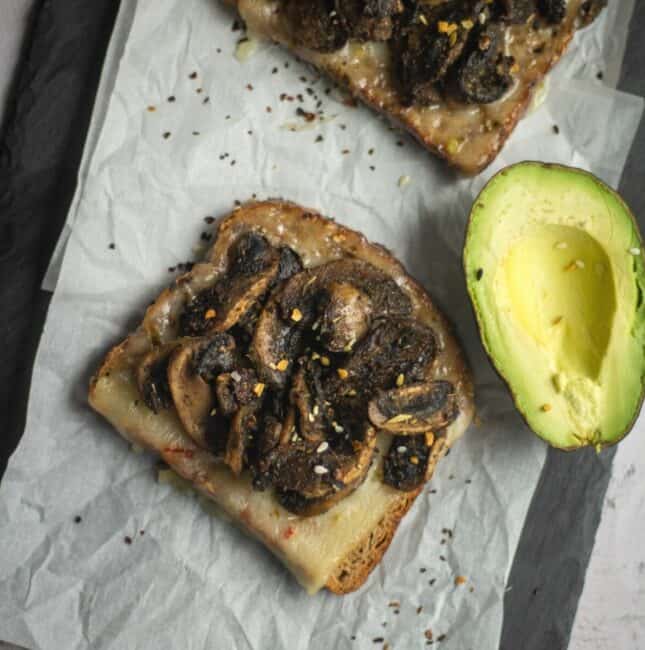 mushroom toast served with avocado placed on a parchment paper