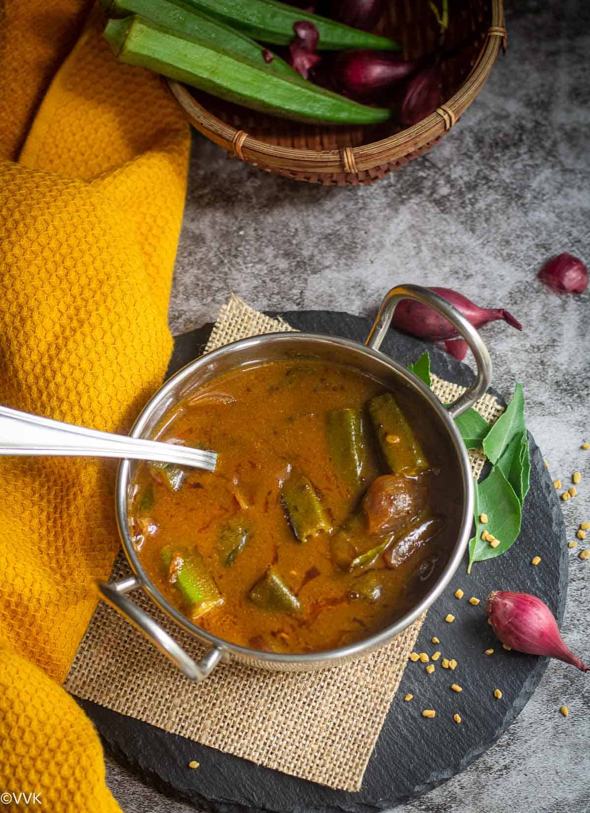 overhead shot of vendakkai gojju in a bowl with a ladle inside