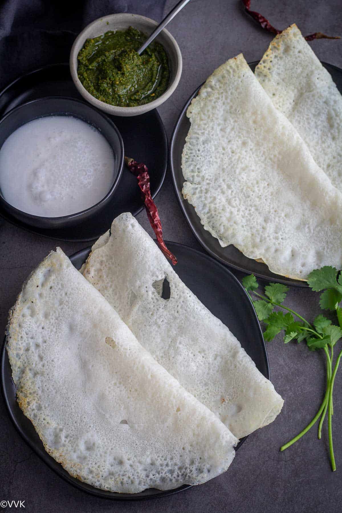 overhead shot of ghavan served with chutney and coconut milk in a black plate