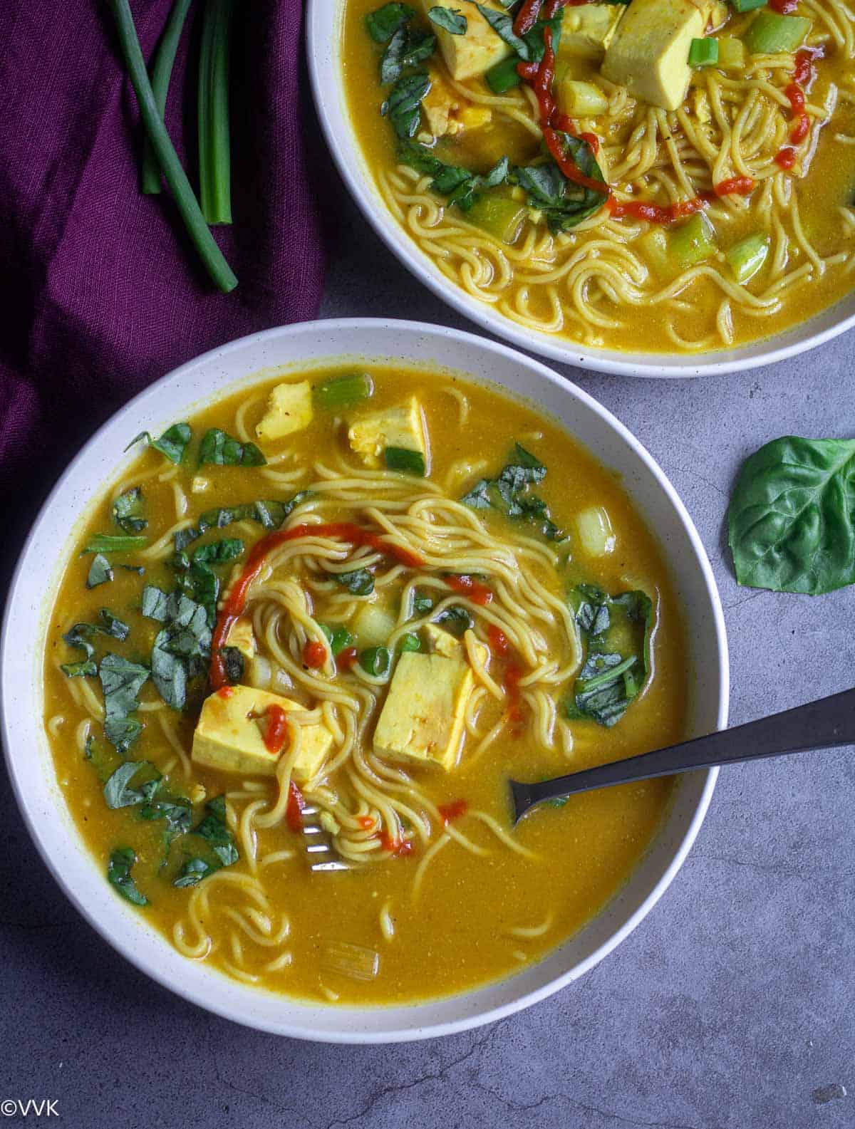 miso ramen soup topped with sriracha and basil served in white bowl