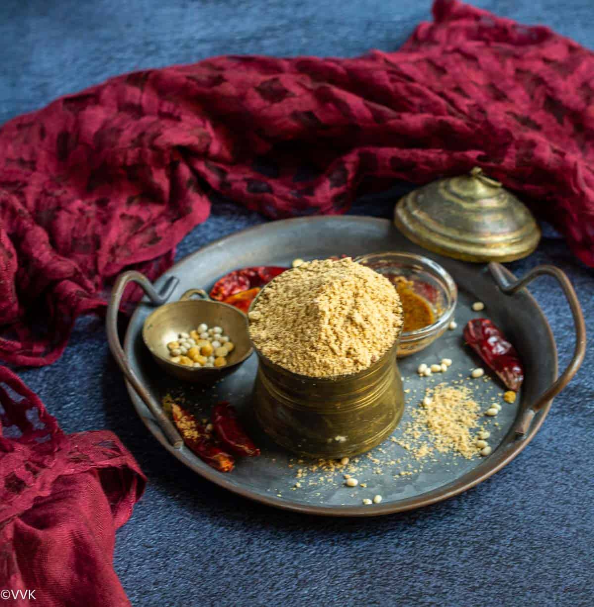 chutney powder in a traditional ware placed on a tray with lentils and chilies on the side