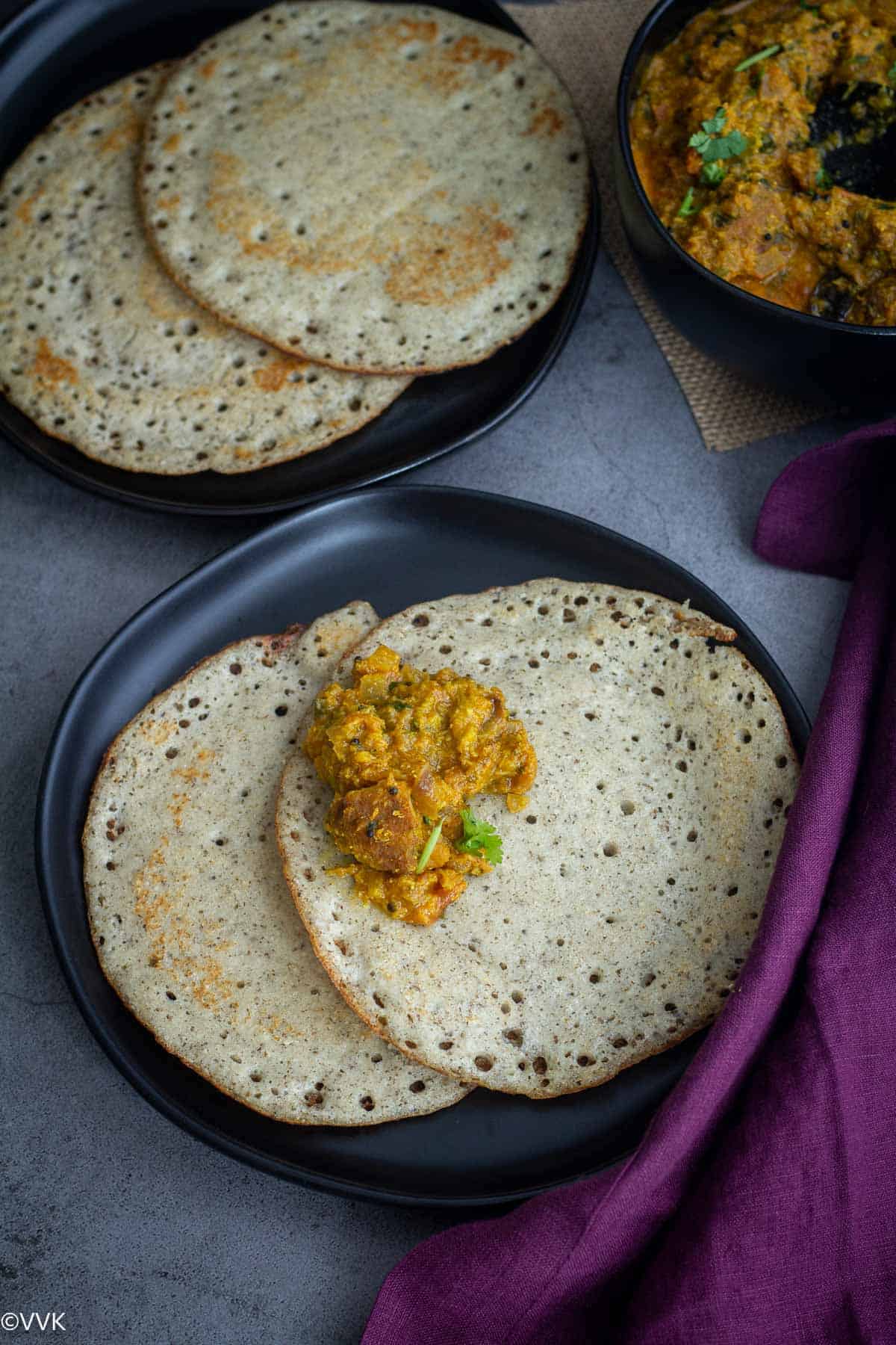 soft and spongy kal dosa served with vada curry in black plate