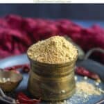 idli podi placed in brassware on a tray with text overlay for pinterest