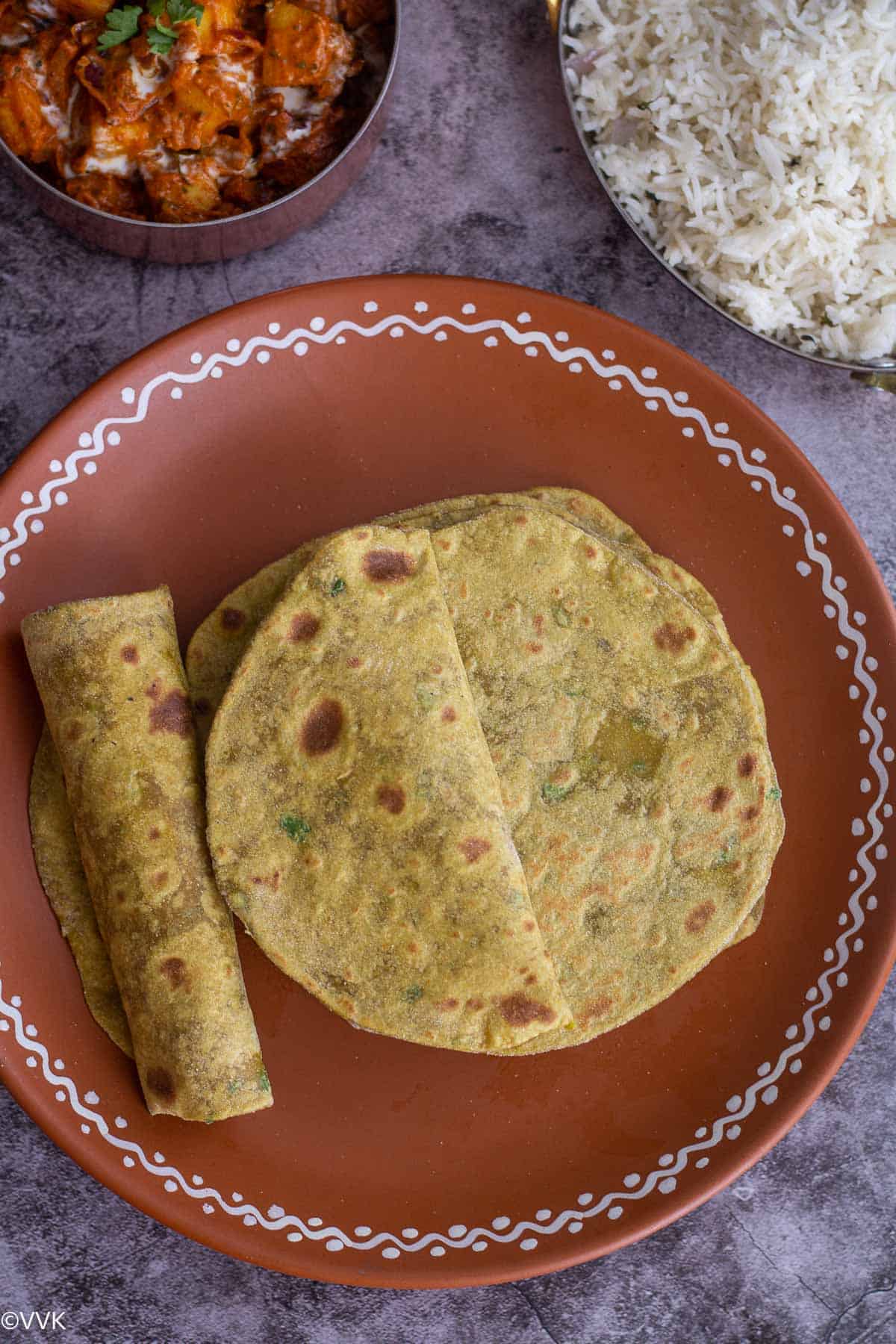 overhead shot of avocado roti served on teracotta plate with rice and curry on the side