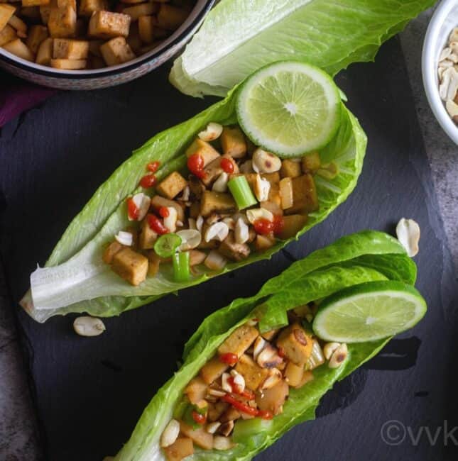 close up shot of lettuce wraps filled with tofu served with lime wedges