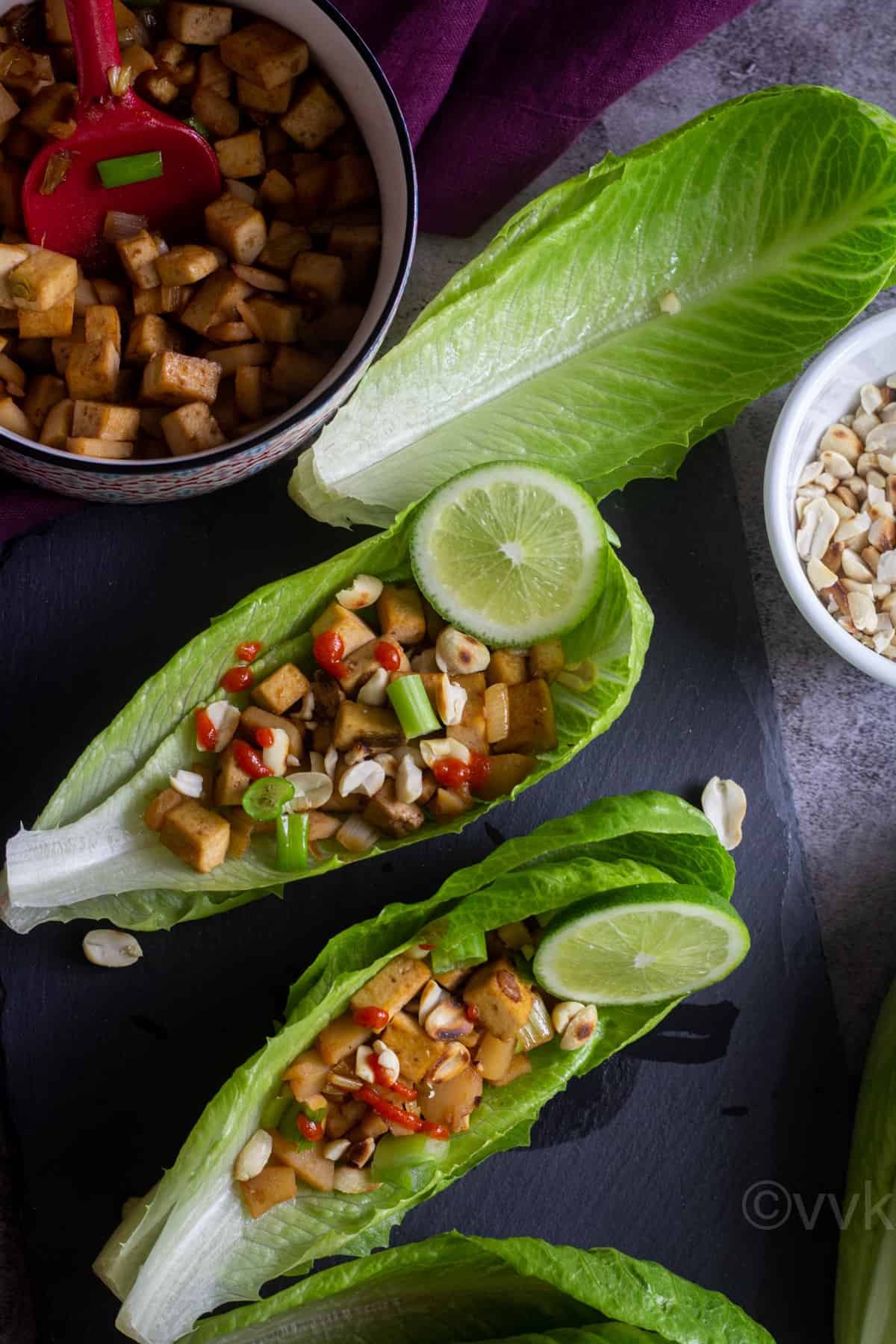 easy lettuce wraps served on a black slate board with the filling and some peanuts on the side