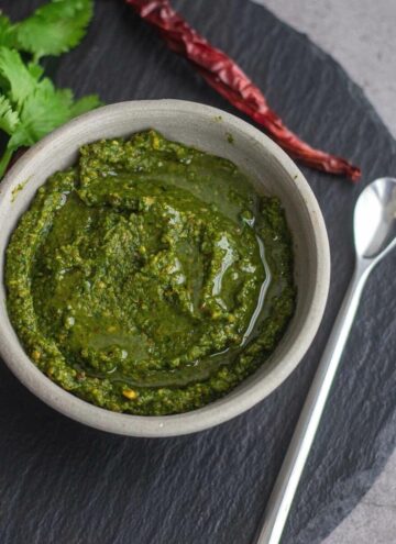 square image of kothamalli chutney served in whiite ceramic bowl placed in black slate board