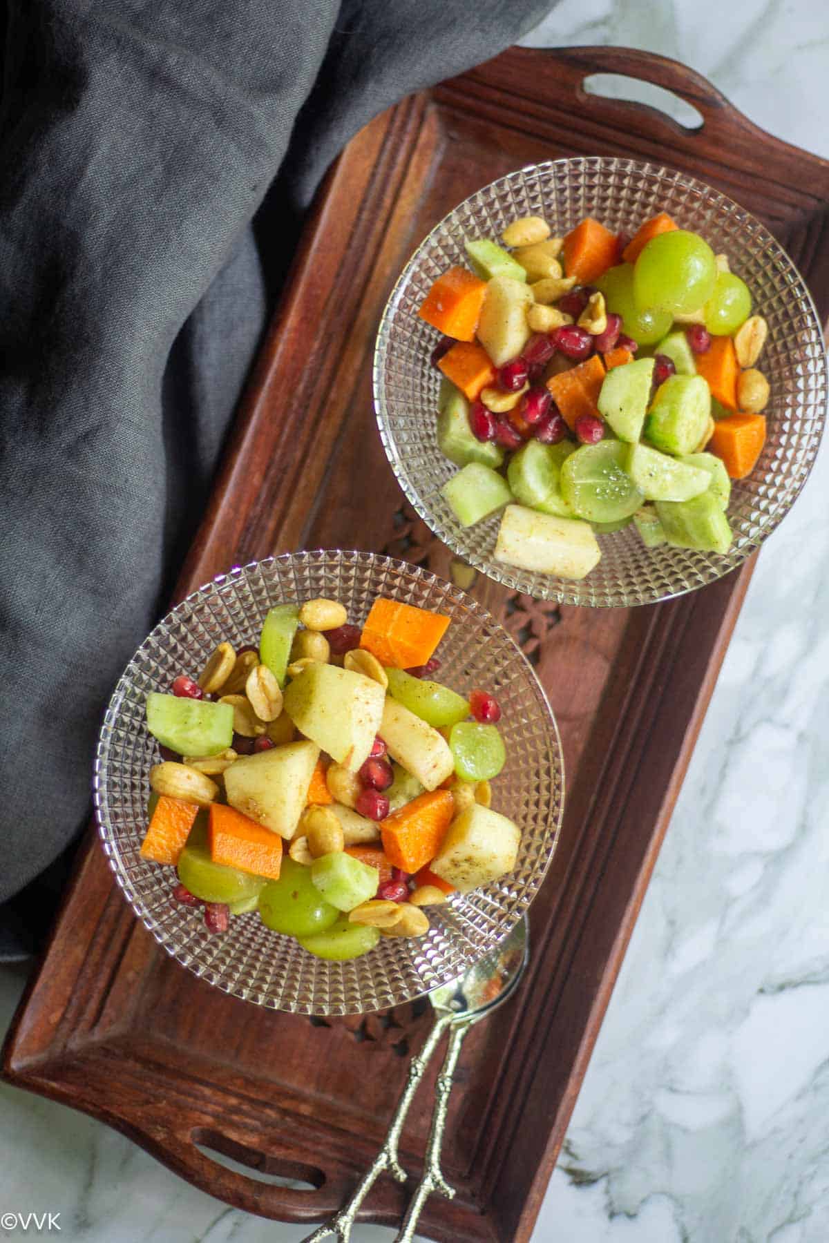 overhead shot of fruit salad served in two bowls placed on wooden board