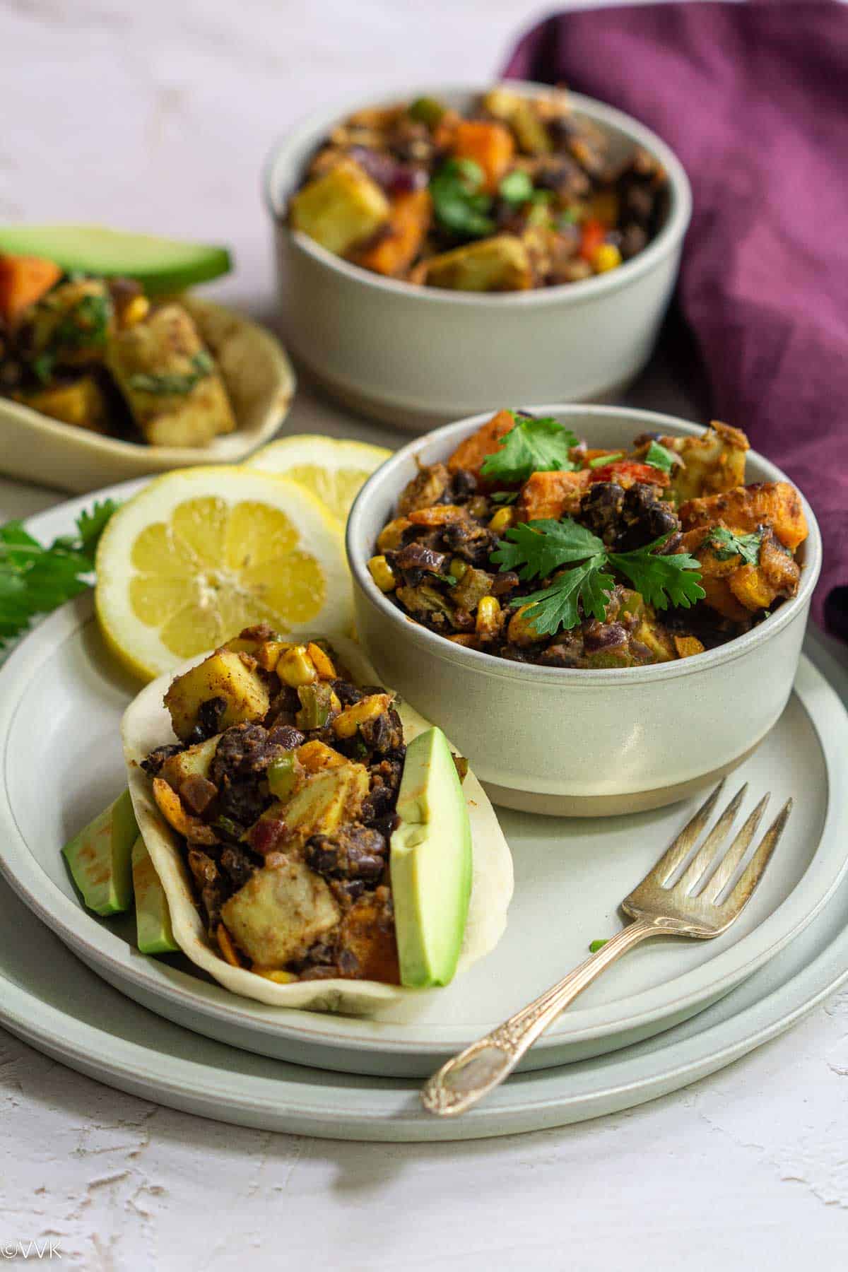 tex-mex veggies served in two bowls and one filled inside taco placed on a plate