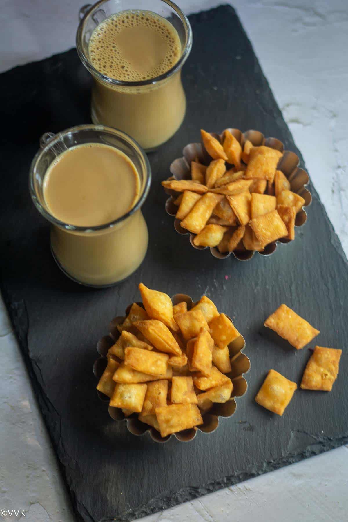 namak para served in two ramekins placed on a black board with coffee