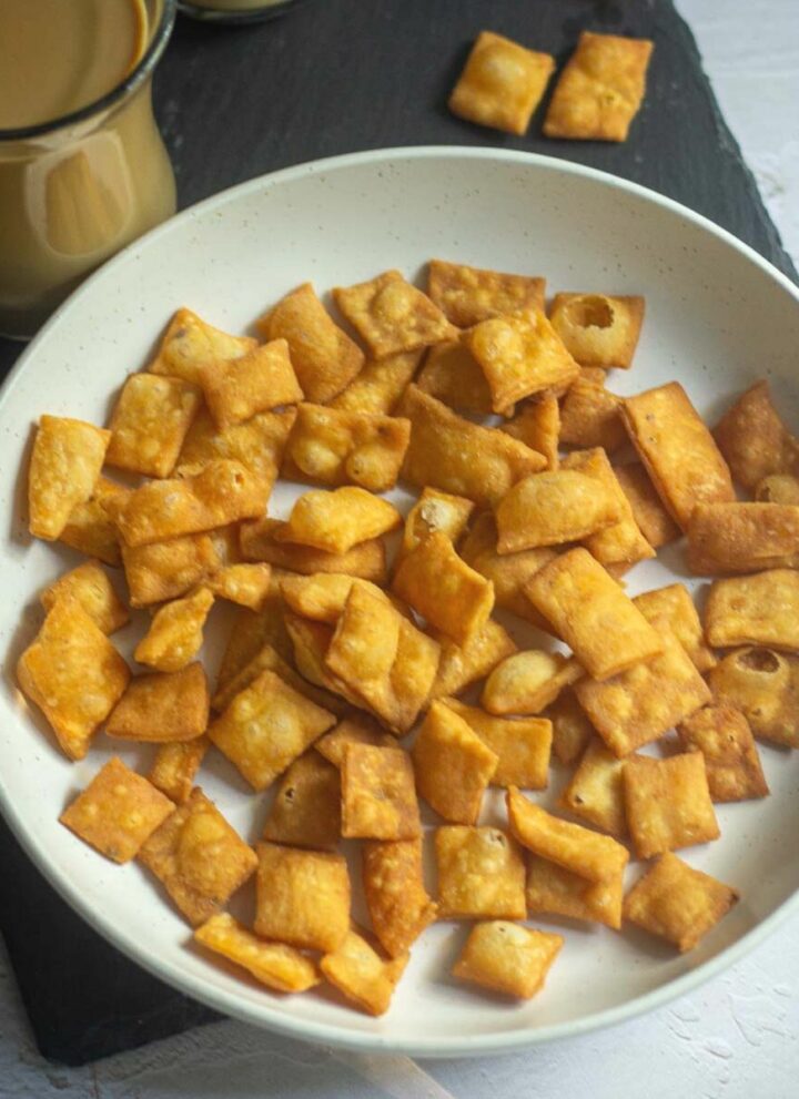 square image of namak para served in white bowl with coffee on the side