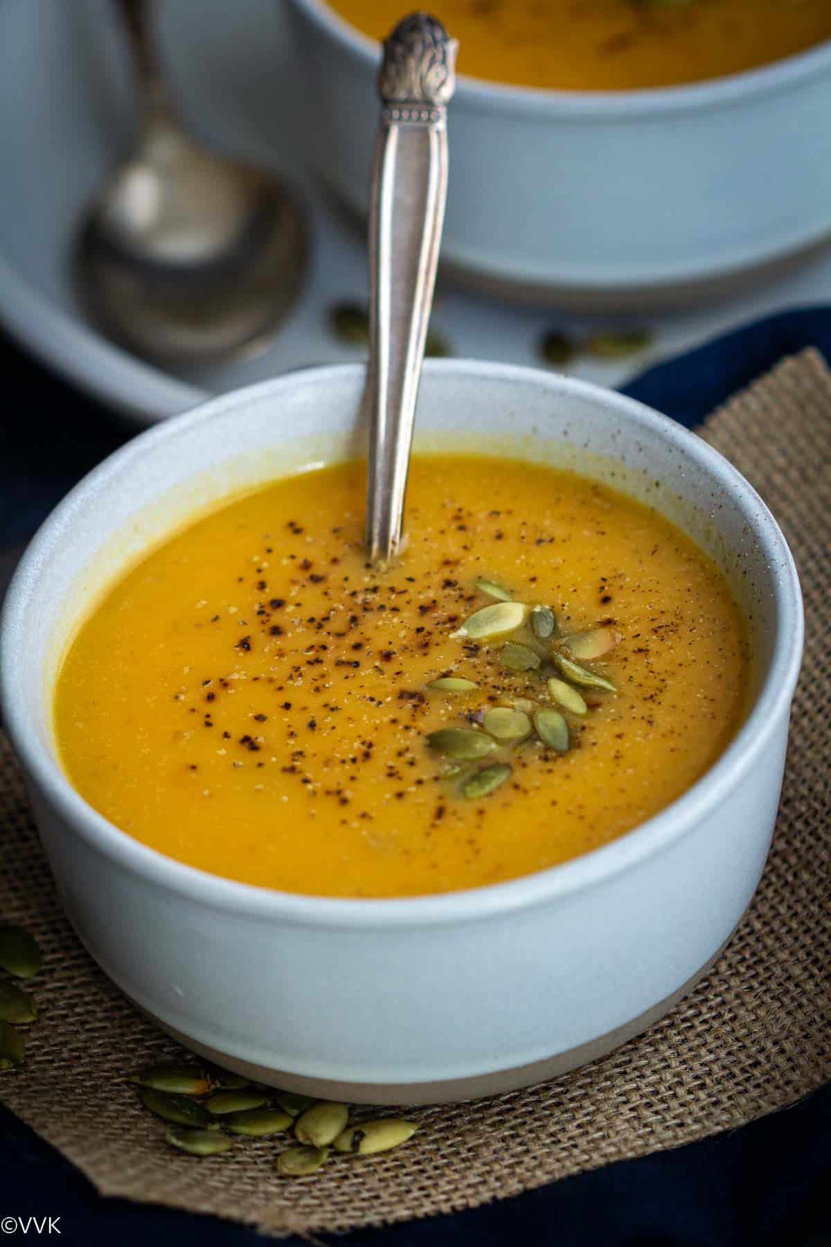 close up shot of instant pot pumpkin soup served in white bowl wih spoon inside