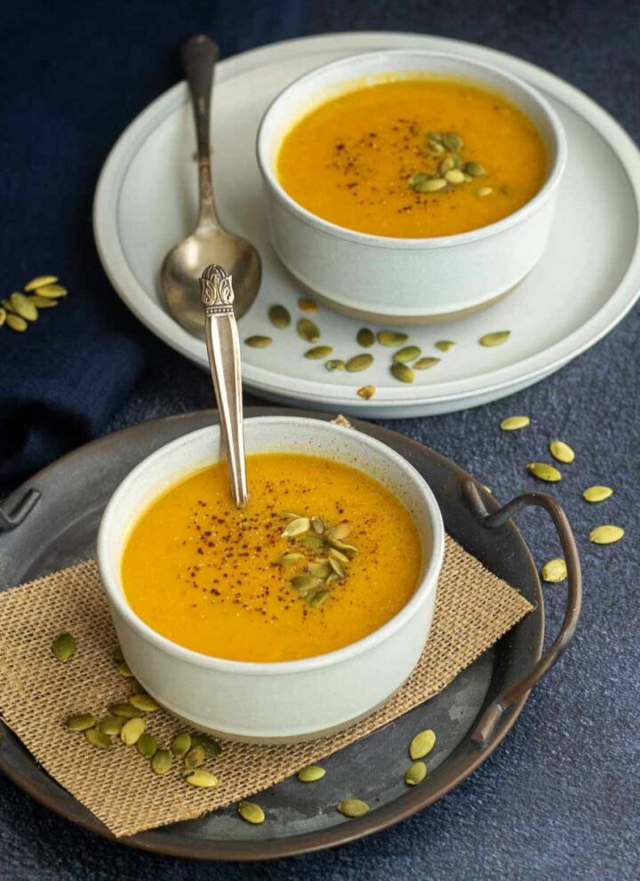 Square image of pumpkin soup served in two bowls