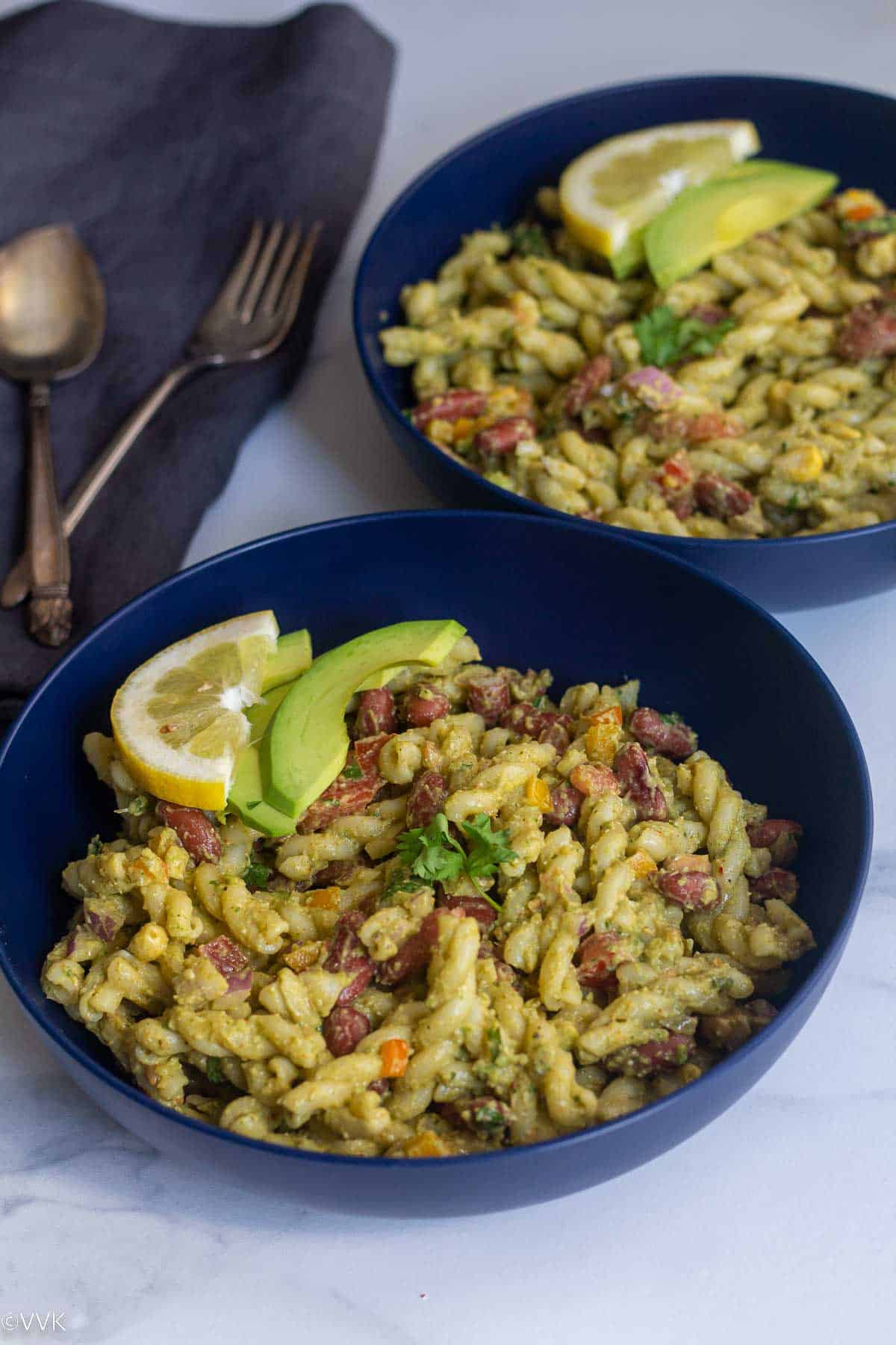 taco pasta salad topped with lemon wedge and avocado slice served in a blue bowl