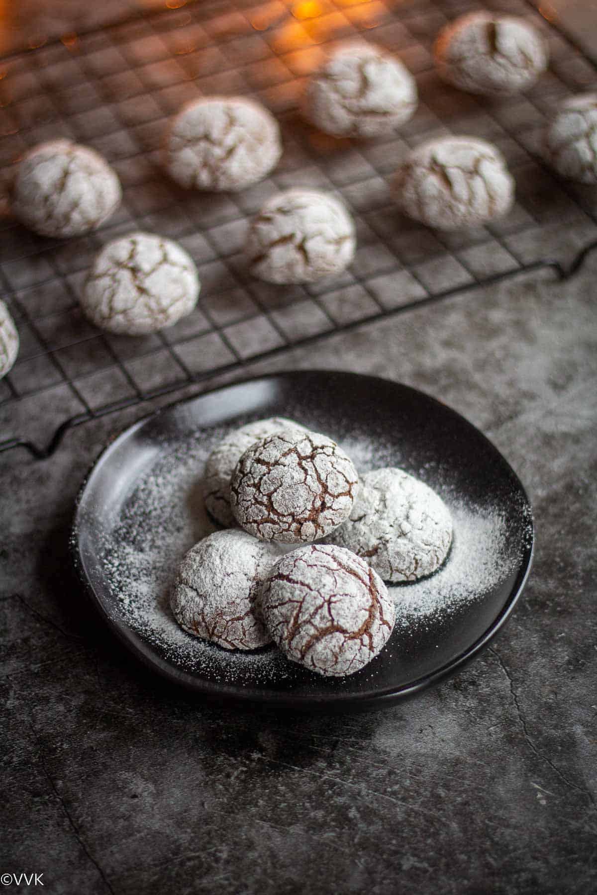 close up shot of eggless chocolate crinkle cookies placed on black plate