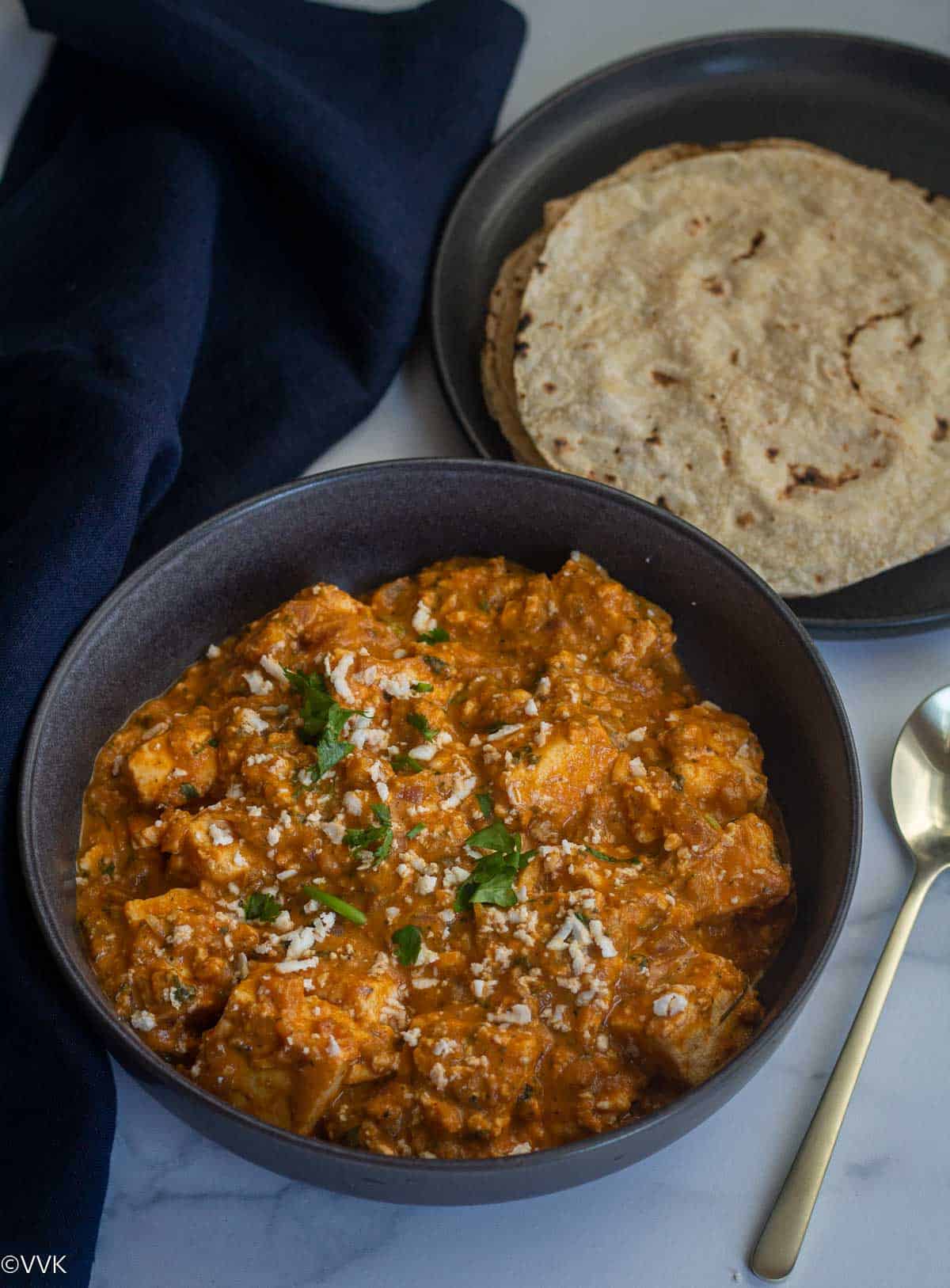 paneer lababdar served with roti with a spoon and blue fabric on the side