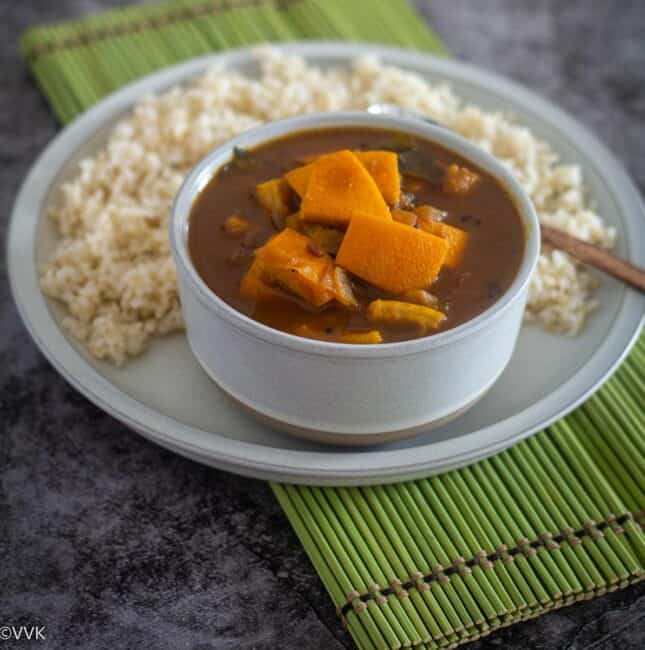 square image of orange peel kuzhambu served with rice