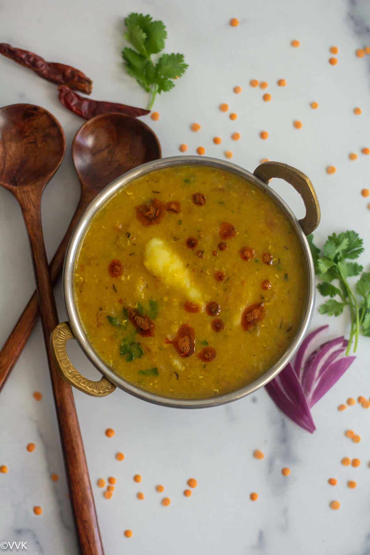 overhead shot of aloo masoor dal served in kadai with red lentils sprinkled