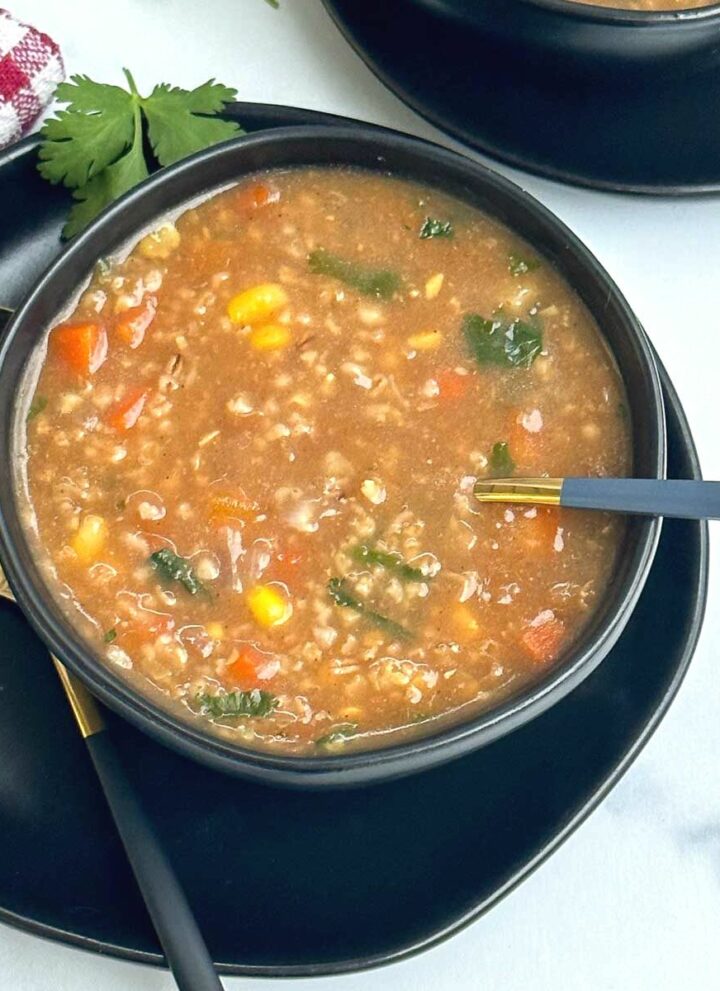 oats soup served in black bowl with spoon inside