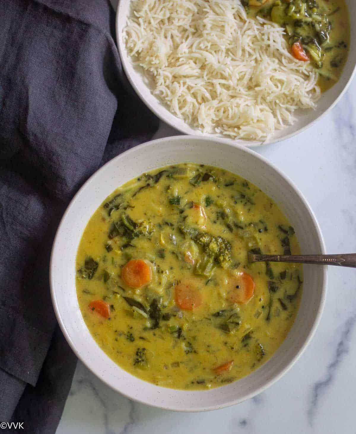 overhead shot of yogurt curry placed in white bowl with spoon