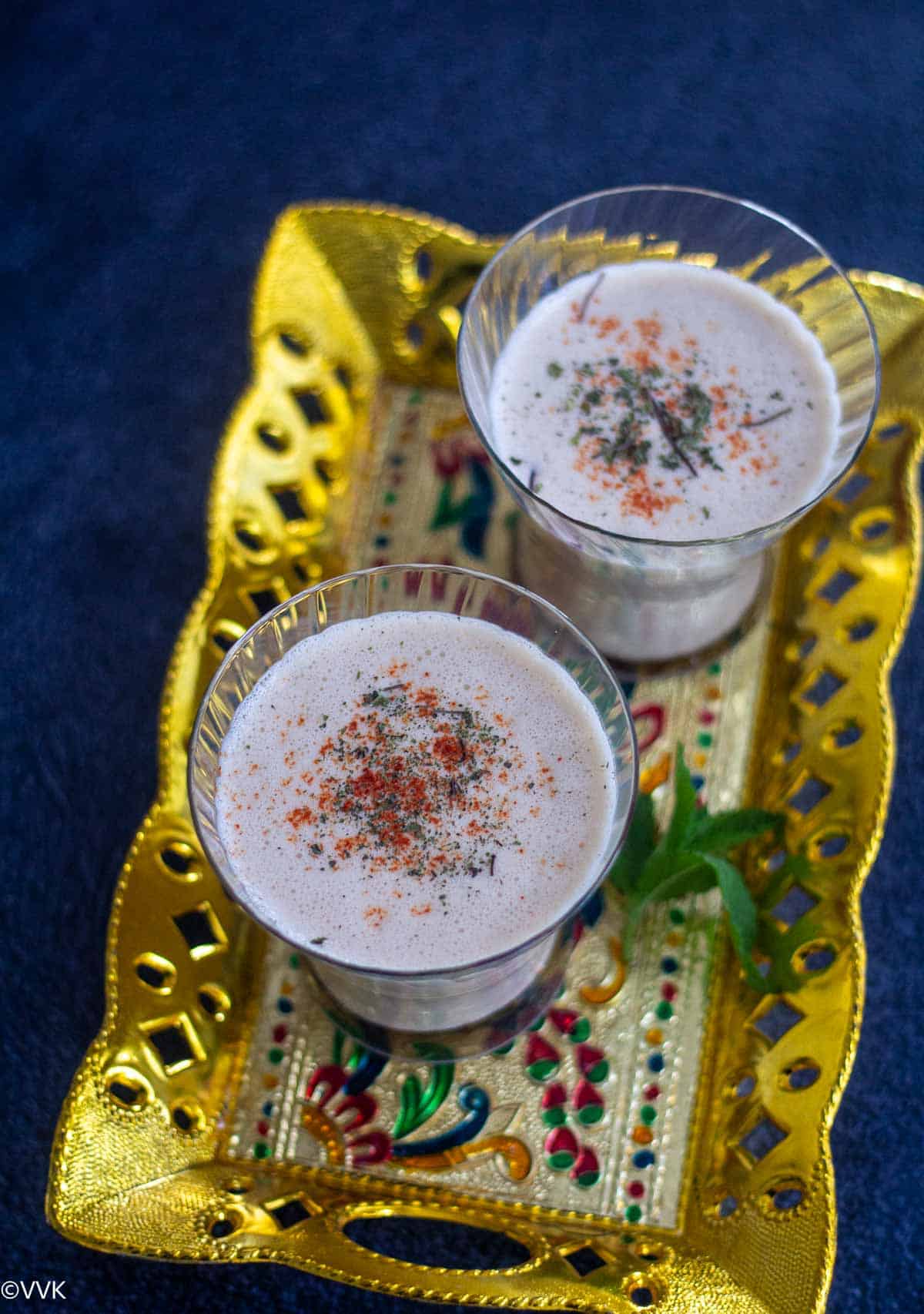 spicy lassi served in two glasses placed on golden tray