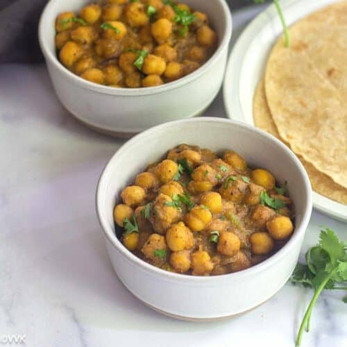 chana kurma served in two white bowls served with roti