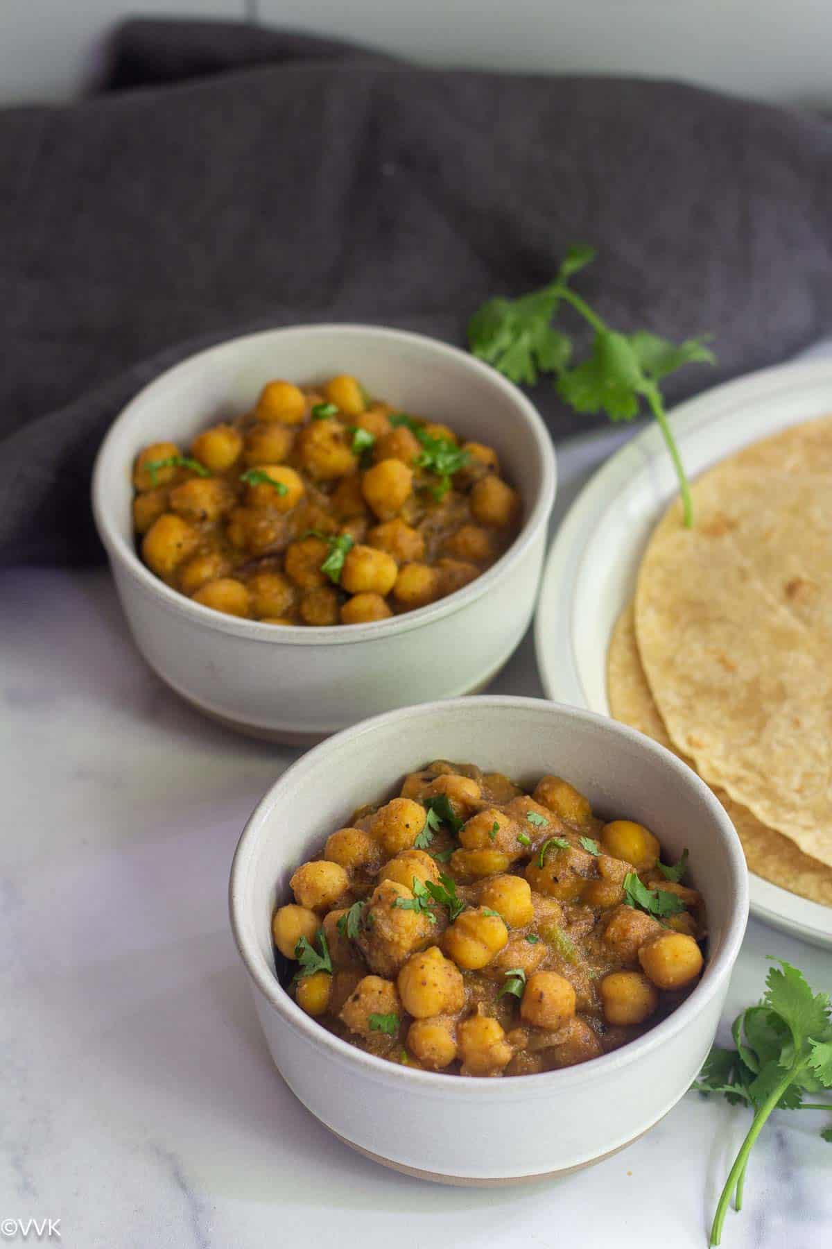 chana masala served in two white bowls