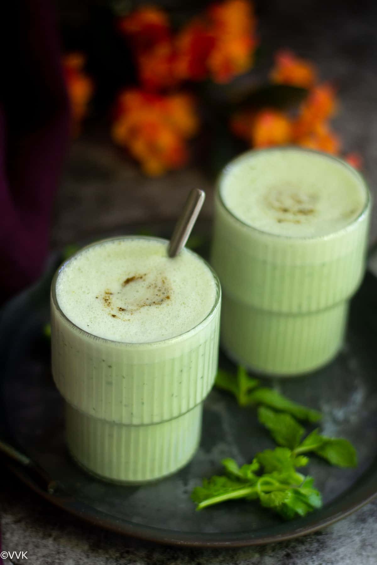 cucumber salt lassi served in two glasses placed on tray