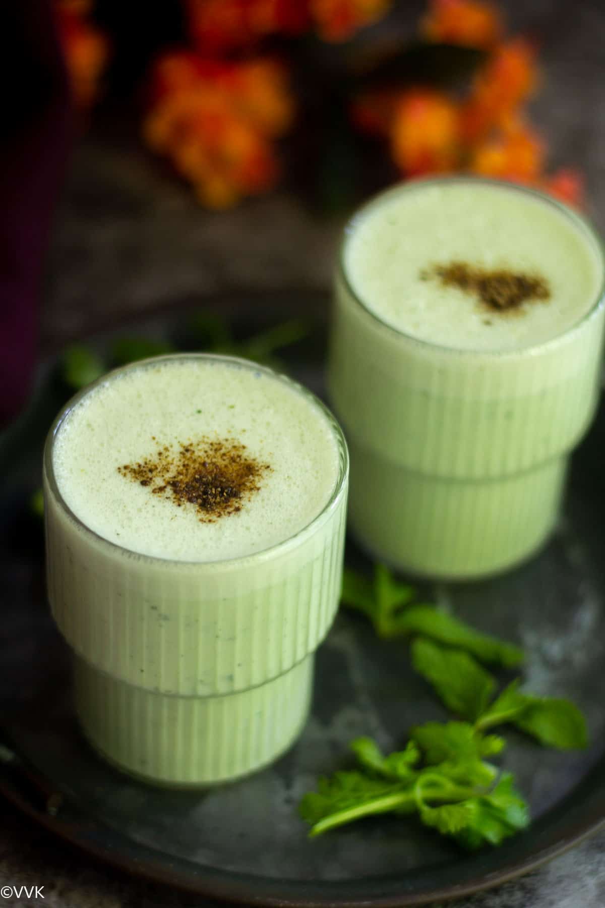 vellarikkai lassi in two glasses sprinkled with chaat masala