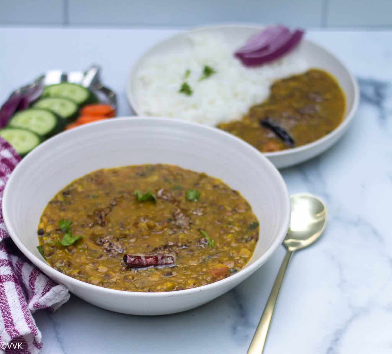 panchmel dal served in white bowl with spoon inside