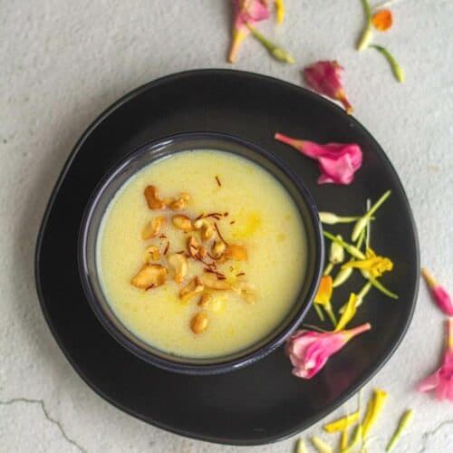 rava payasam served in black bowl with flowers on the side