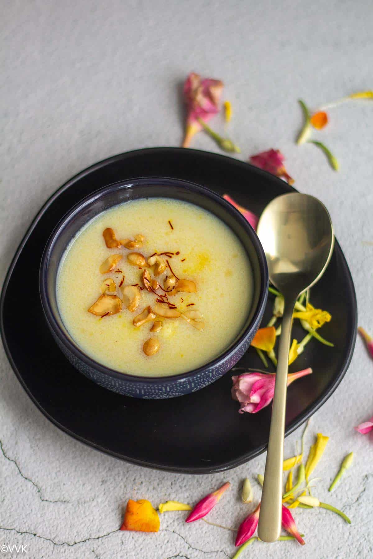 close up shot of sooji kheer served in black bowl with spoon on the side
