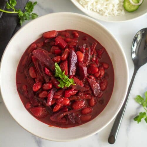 overhead shot of beetroot curry served in white bowl