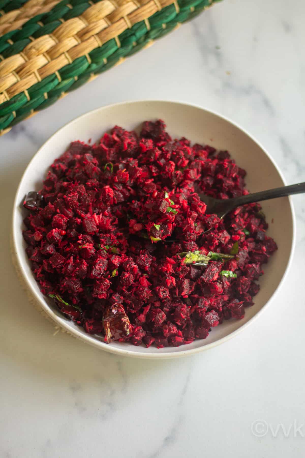 beets stir fry served in white bowl with a spoon inside