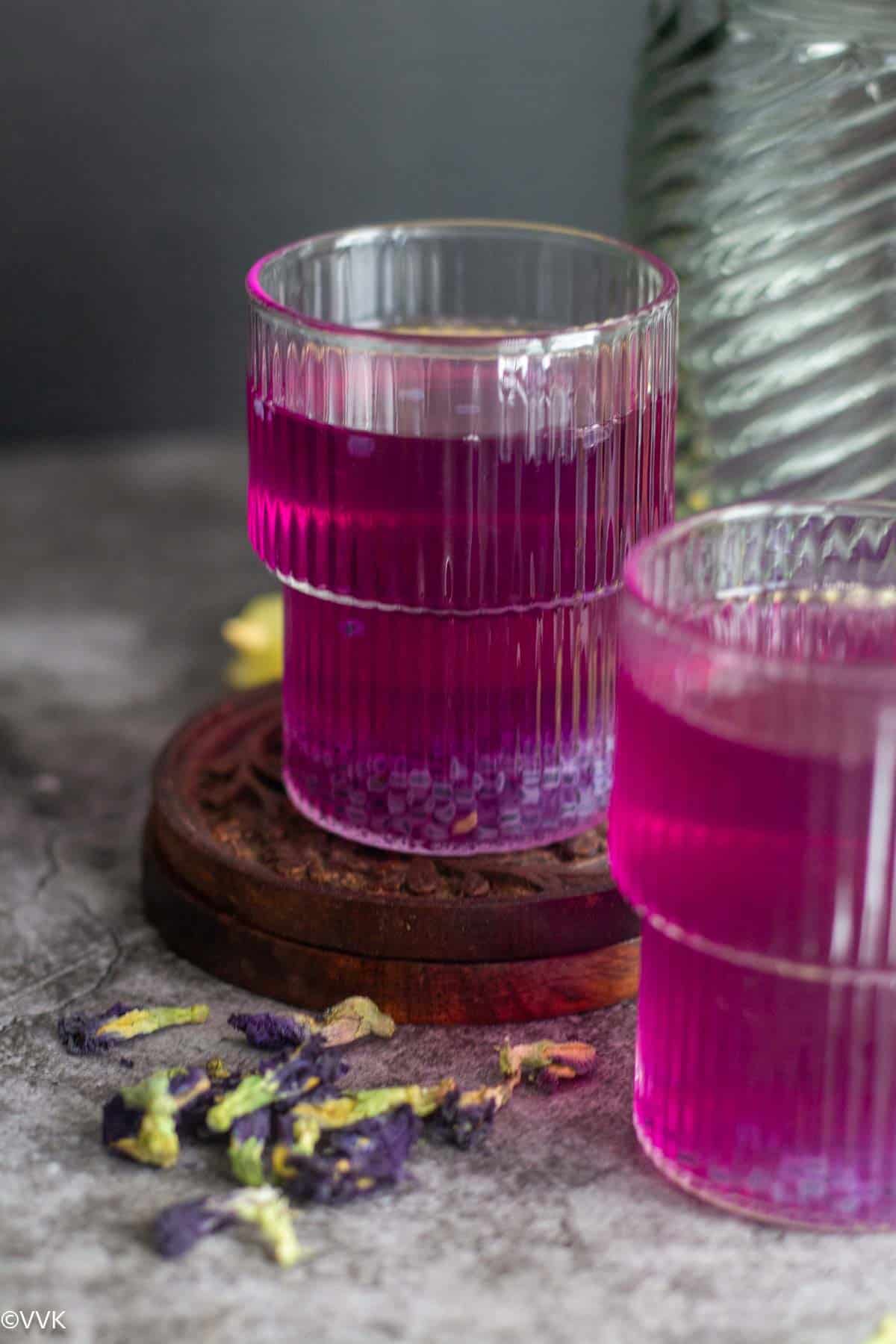 straight shot of blue lemonade with dried flowers on the side