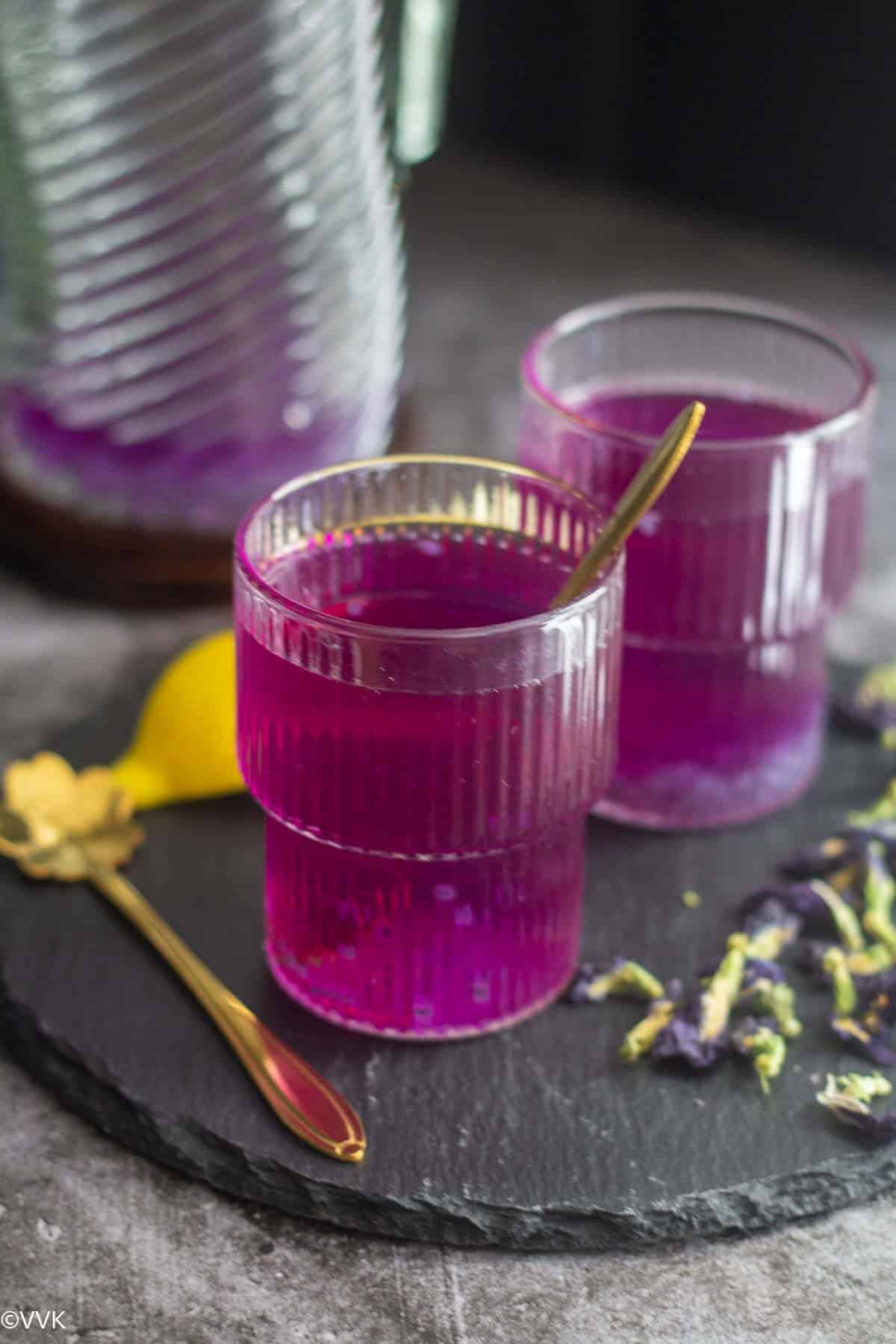 purple lemonade served in two glasses with a spoon inside