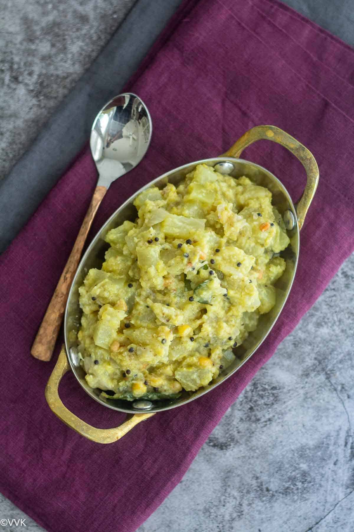 overhead shot of green papaya kootu with spoon the side